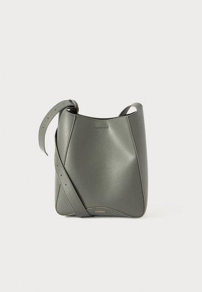 Sac seau en cuir vert avec une texture lisse, une bandoulière réglable, un design géométrique et des détails minimalistes.