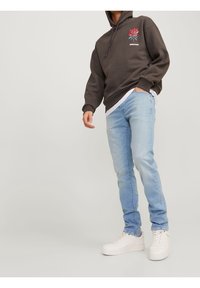 Tmavě šedá mikina s grafikou růže na hrudi, spárovaná s světle modrými slim džínami a bílými teniskami. Neformální streetwear outfit.