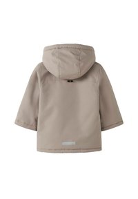 Lys beige jakke med hætte, korte ærmer og en glat tekstur. Har en reflekterende detalje på ryggen for synlighed.