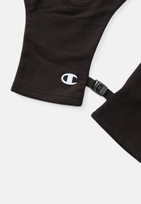 Zwarte sportleggingen met een wit logo en een zijkantstrap met een gesp. Gladde textuur met verstevigde stiksels aan de randen.