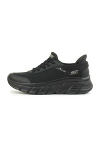 Scarpe sportive nere con tomaia in mesh testurizzato, suola spessa e ammortizzata, e punta rinforzata. Presentano lacci piatti e dettagli del logo sul lato.