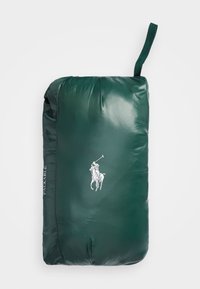 Grüne verpackbare Jacke mit glatzer Textur, versehen mit einem weißen Logo und dem Text "PACKABLE" an der Seite. Mit einer Aufhängeöse an der Oberseite.