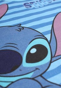 Tissu bleu présentant un personnage de dessin animé aux grands yeux et au sourire, sur un fond rayé bleu et rose.