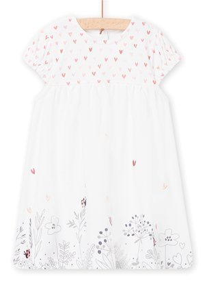 Hvid babydragt med lyserøde hjerte-mønstre øverst og grå blomsterdesigns med mariehøns nederst, vist på en træbøjle.