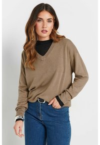 Brauner V-Ausschnitt-Pullover mit langen Ärmeln, über einem schwarzen Oberteil getragen, kombiniert mit blauen Jeans. Der Stoff wirkt weich und leicht strukturiert.