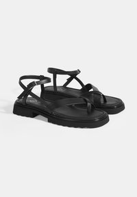 Zwarte sandalen met platte zolen, een verstelbare enkelband en kruislings aangebrachte banden. Gemaakt van soepel leer met een gestructureerde voetbed.