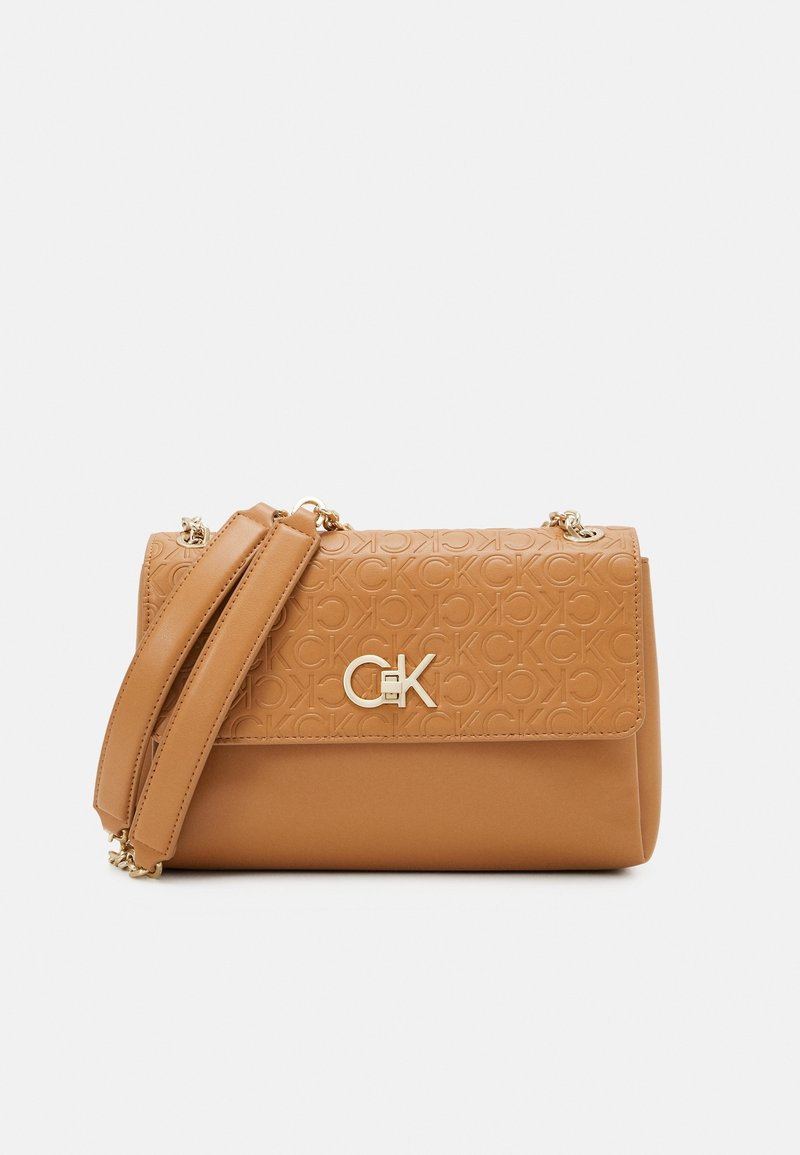 Sac à bandoulière en cuir camel avec motif CK embossé, logo CK doré sur le rabat et sangle rembourrée avec accents de chaîne dorée.
