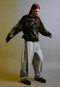 Svart och grå oversized tröja med fluffig textur, i kombination med ljusgrå baggy byxor och svarta platåskor. Minimalistisk design, inga mönster.