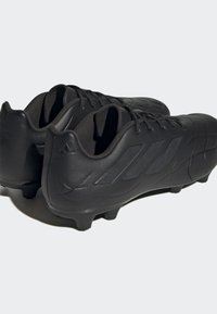 Botas de fútbol negras con una textura de cuero suave, que cuentan con un diseño de bajo perfil y lados con patrones para mejorar el agarre y el rendimiento.