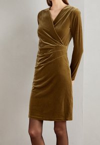 Robe en velours vert olive avec un design portefeuille, des manches longues et des détails froncés à la taille. Texture lisse, coupe mi-longue jusqu'aux genoux.