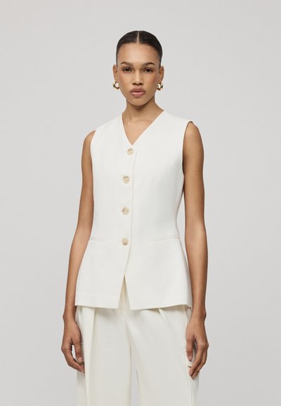 White sleeveless vest with a v-neckline, four large cream buttons, and two side pockets, featuring a tailored fit and smooth texture.