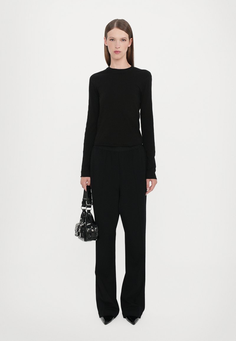 Black long-sleeve top and tailored wide-leg pants, paired with a small black handbag. All items are in solid black, featuring sleek materials.
