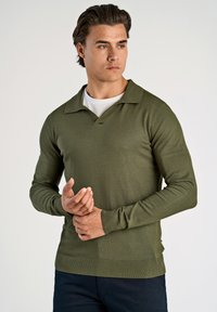 Olivengrüner Strickpullover mit V-Ausschnitt und langen Ärmeln. Das Material ist glatt und hat einen gerippten Saum sowie Manschetten für zusätzliche Textur.