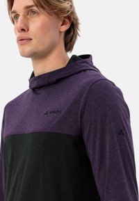 Felpa con cappuccio realizzata in tessuto misto; presenta un design a blocchi di colore con viola nella parte superiore e nero nella parte inferiore, logo discreto sul petto e sulla manica.