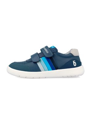Zapatilla deportiva azul marino con franjas en azul claro y oscuro, dos correas de velcro, suela blanca, lengüeta trasera gris y un pequeño logo blanco en forma de "b" en el lateral.