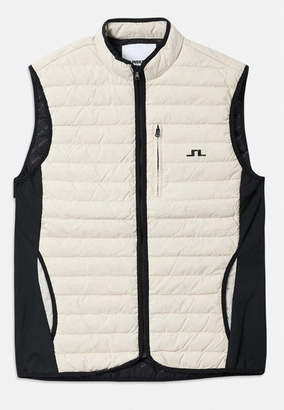 Gilet léger avec un devant matelassé crème et des panneaux latéraux noirs. Présente des poches zippées et un col haut. Marquage sur la poitrine.