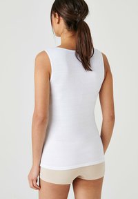 Witte mouwloze top in een aansluitend ontwerp, gemaakt van ribbelstof, met een ronde halslijn en een gladde textuur. Draag met beige shorts.