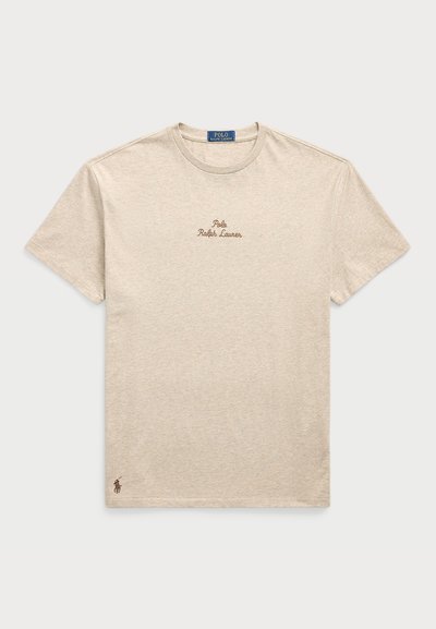 Bežs kokvilnas T-kreklis ar īsām piedurknēm, apaļu kaklu, ar izšūtu "Polo Ralph Lauren" logo brūnā krāsā un mazu logo emblēmu uz apakšmalas.