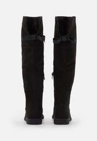 Black suede over-the-knee boots with a smooth texture, featuring a soft interior, tied ribbon accents, and side zippers.