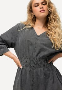 Vestito in denim grigio con scollatura a V, maniche larghe e cintura elastica, caratterizzato da sottili righe verticali e una vestibilità comoda.