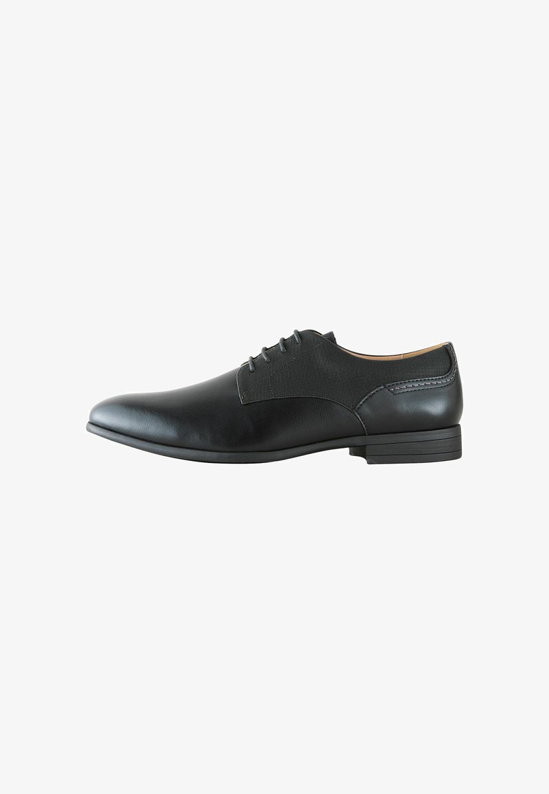 Chaussure habillée noire pour homme avec fermeture à lacets, bout lisse, panneaux latéraux texturés et talon bas empilé, présentée en profil latéral sur fond blanc.