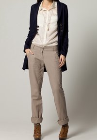 Laivastonsininen pitkä takki, kerma valkoinen paita, beigeihin käännettyihin housuihin ja ruskeat nauhalliset saappaat kuvioiduilla sukilla. Yksinkertainen muotoilu, räätälöity istuvuus, monipuoliset värit.