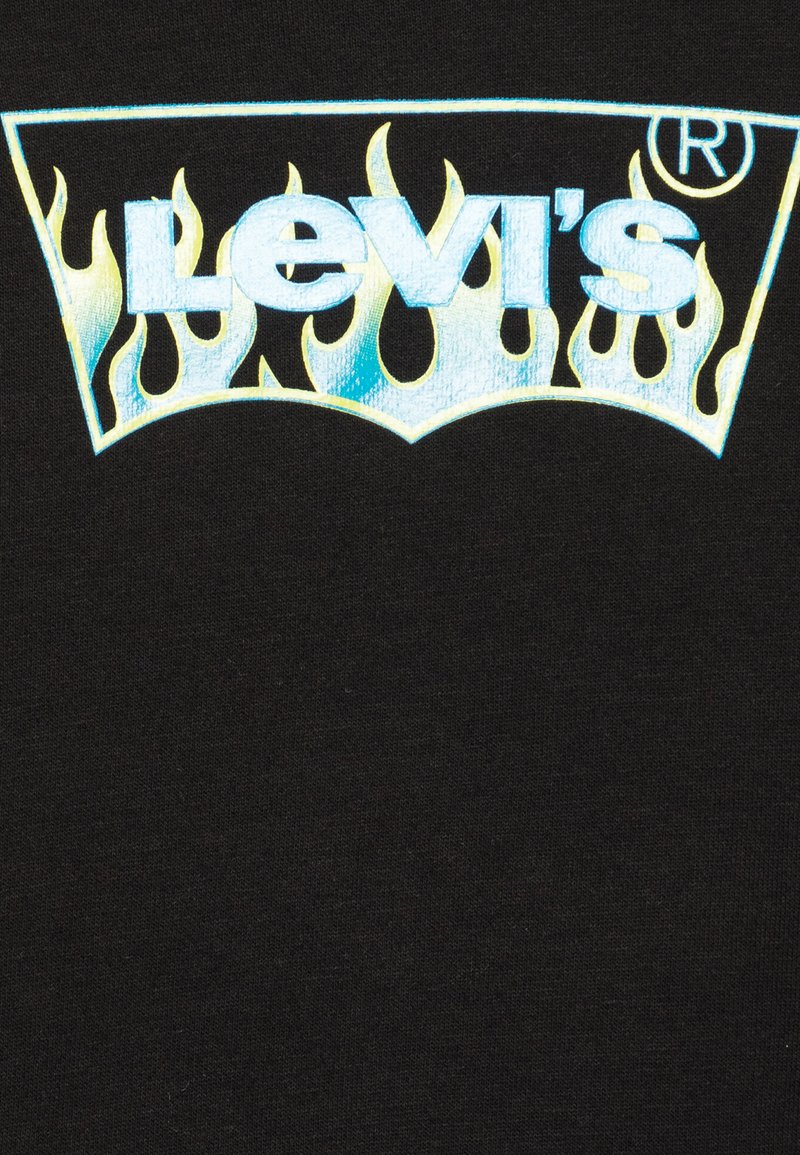 T-shirt noir avec un logo Levi's en flammes réfléchissantes bleues et jaunes, centré sur la poitrine, avec une texture lisse et un design décontracté.