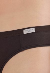 Bruna bomullsunderkläder med en mjuk textur och en etikett märkt "intimissimi Natural." Har en låg midja-design och elastisk midjeband.