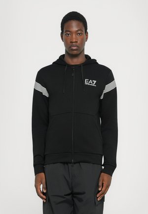 Felpa nera con zip e tasca a marsupio, con strisce bianche sulle spalle e logo EA7 sul lato sinistro del petto. Realizzata in tessuto morbido.
