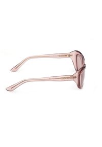 Lunettes de soleil surdimensionnées translucides roses avec des verres teintés marron et le logo "GUESS" sur la branche, vues de profil sur un fond blanc.
