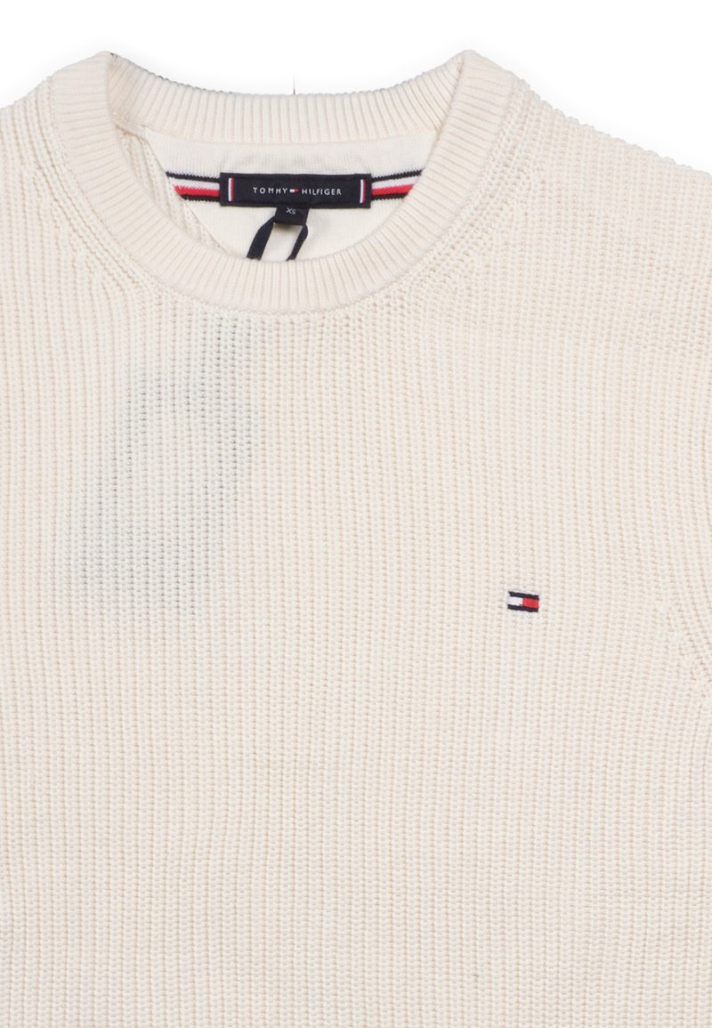 Pullover aus gestricktem Material in Cremefarbe mit Rundhalsausschnitt, verziert mit einem kleinen gestickten Logo in Rot, Weiß und Blau auf der Brust.