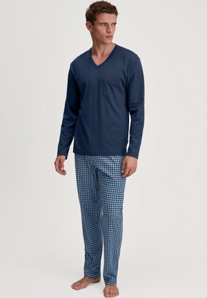 Haut bleu marine à manches longues avec un col en V, doté d'une poche poitrine, associé à un pantalon bleu clair affichant un motif géométrique dans des tons de bleu foncé.