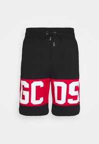Shorts noirs avec de larges bandes rouges près de l'ourlet, affichant de grandes lettres blanches en bloc "GCDS" sur le devant et une taille à cordon noir.