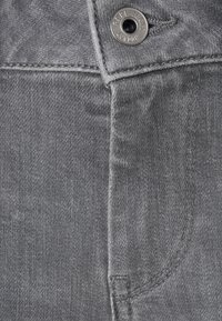 Jeans de mezclilla gris con cierre de cremallera y botón, con detalles de costura visibles y un pequeño botón de marca etiquetado "Pepe Jeans London".