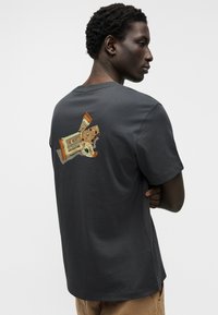 Σκούρο γκρι μπλουζάκι από μαλακό ύφασμα, με πολύχρωμο γραφικό ενός σνακ μπαρ στην πλάτη, με στρογγυλή λαιμόκοψη και κοντά μανίκια.