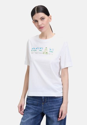 T-shirt blanc à manches courtes, avec une inscription multicolore "OCEAN". Fabriqué en coton avec une texture lisse. Coupe décontractée.