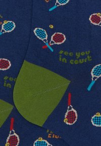 Calzini blu navy con motivi di racchette da tennis in rosso, blu e giallo, con un'accattivante line verde al polsino e la scritta "ci vediamo in campo."