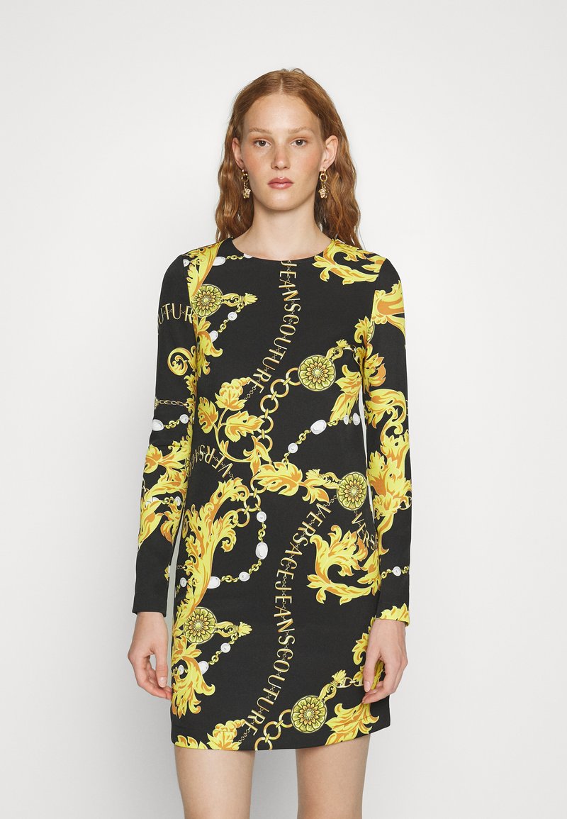 Abito lungo nero con maniche lunghe, caratterizzato da un audace motivo barocco giallo e dettagli bianchi, con scollo rotondo e silhouette aderente.