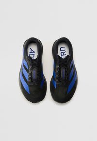 Baskets de sport noires avec des rayures bleues. Tige en maille, bout arrondi et semelle en caoutchouc. Marque visible sur la languette et la semelle intérieure.