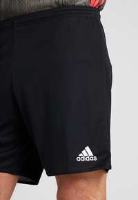 Black athletic shorts made of lightweight fabric. Features white Adidas logo and a structured waistband. Smooth texture, no visible patterns.