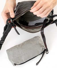 Svart läderhandväska med ett dragkedjeöppning, med ett randigt tyginteriör och en liten randig påse inuti.