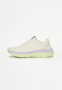 Ανοιχτό μπεζ αθλητικό παπούτσι με υφασμάτινη επάνω επιφάνεια με υφή, μωβ μεσαία σόλα, πράσινη σόλα και μαύρη λεπτομέρεια κοντά στην περιοχή των κορδονιών. Διακρίνεται για την απορρόφηση κραδασμών.