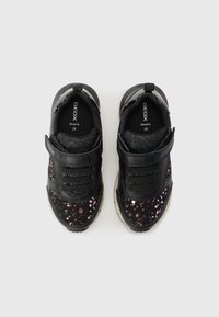 Mustad vabaajajalatsid tekstuurse viimistlusega, esiküljel sädelevate roosa ja lilla täppidega ning Velcro kinnitusrihmadega.