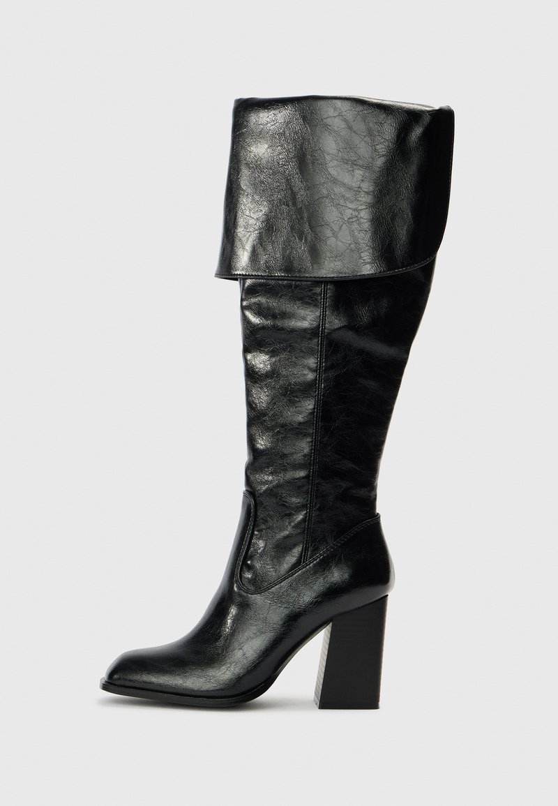 Black knee-high leather boot with folded cuff, pointed toe, and block high heel, shown in side profile on a plain background.
