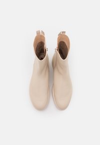 Beige ankle boots made of smooth leather with a rounded toe, featuring a side zipper and soft interior lining.