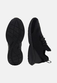 Pár čiernych športových tenisiek, jedna z nich ukazuje štruktúrovanú podrážku s brandingom "Boggi Milano", druhá bočný pohľad na pletený zvršok a úchyt.