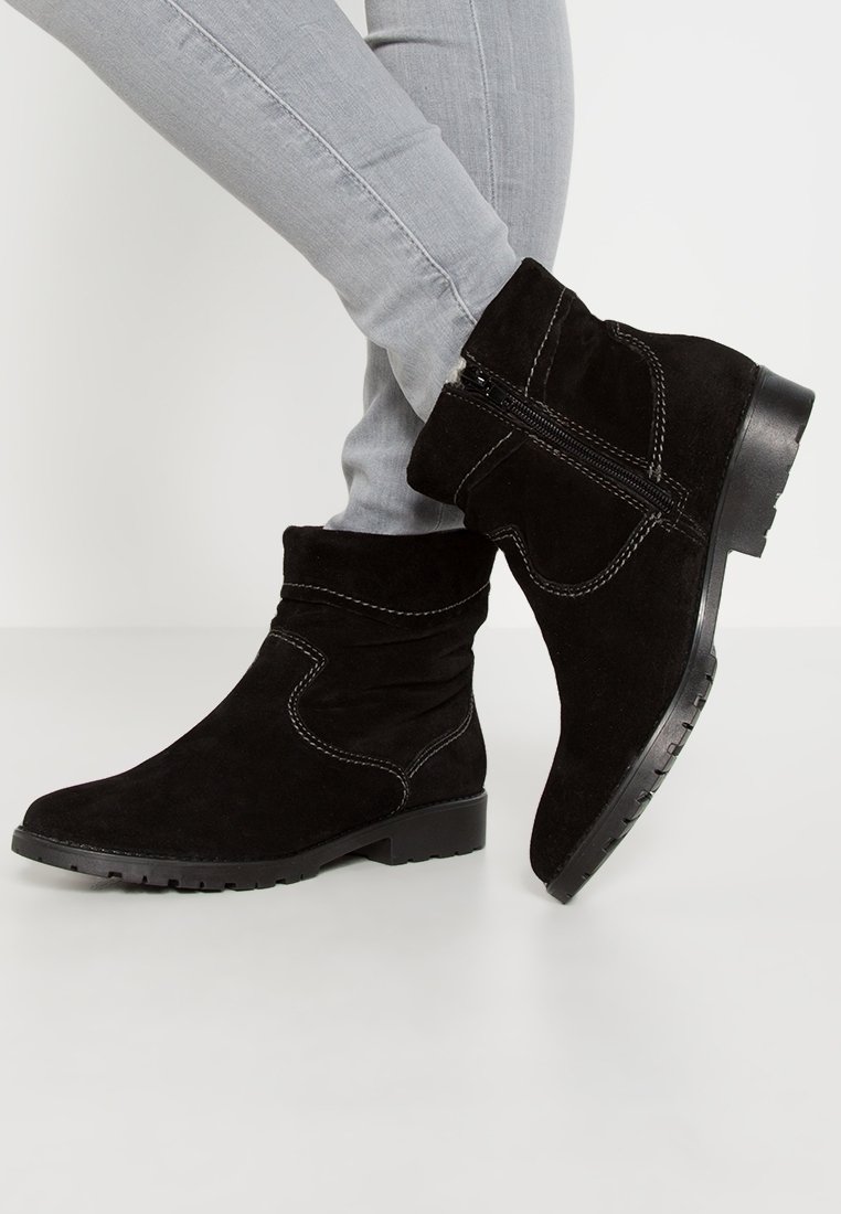 Botas de tobillo de ante negro con un diseño arrugado, que presentan costuras blancas y una cremallera lateral, montadas sobre una suela de goma texturizada.