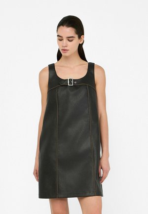 Black leather sleeveless dress with a square neckline, featuring a central silver buckle and contrasting brown stitching. Smooth texture.