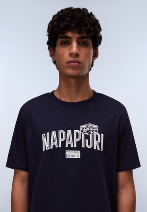 Navy blue cotton t-shirt featuring white text "NAPAPIJRI" and a logo on the upper left. Short sleeves and a crew neckline. Plain texture.