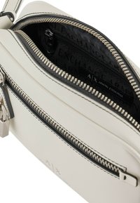 Borsa a tracolla bianca in pelle con interno testurizzato, zip nera, dettagli in argento e marchio Armani Exchange all'interno.